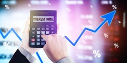 Close up of businessman hands calculating interest rate by using a calculator with upward arrow background
