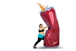 Diet concept. Overweight woman punching a can of soft drink. Isolated on white background