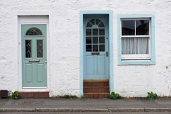 Rough white wall with green and blue door with window