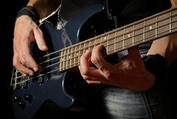 closeup shot of bass guitar in hands of musician
