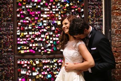 Bride and groom near a gate full with padlocks