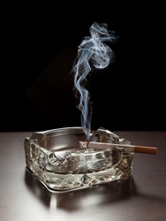 Smoke rising from a cigarette in an ashtray.