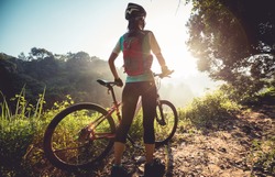 Young woman cyclist  enjoy the beautiful sunrise on summer forest trail