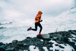 Woman trail runner cross country running up to winter snow mountain top