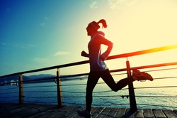 healthy lifestyle sports woman running on wooden boardwalk sunrise seaside 