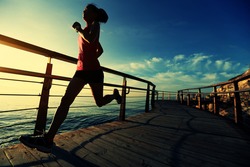 healthy lifestyle sports woman running on wooden boardwalk sunrise seaside 