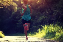 Runner athlete running on forest trail. woman fitness jogging workout wellness concept. 