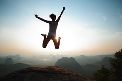 Successful freedom woman jumping on sunrise mountain top
