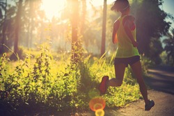 Young fitness woman running at morning tropical forest trail 
