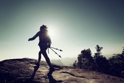 successful woman hiker walking on mountain clifftop at sunrise