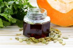 organic pumpkin oil in a glass jar on a wooden table
