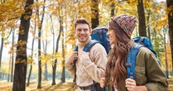 adventure, travel, tourism, hike and people concept - couple of travelers with backpacks over autumn park background