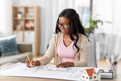 architecture, building, construction and real estate concept - african american female architect with blueprint, ruler and notebook working at home office