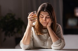 alcoholism, alcohol addiction and people concept - drunk woman or female alcoholic drinking whiskey at home