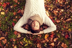 season, happiness and people concept - smiling young man lying on ground or grass and fallen leaves in autumn park