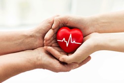 charity, health care, donation and medicine concept - man hand giving red heart with cardiogram to woman