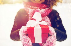 winter holidays, christmas and people concept - close up of happy woman with present or gift box outdoors