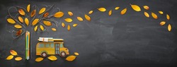 Back to school concept. Top view banner of school bus and pencils next to tree sketch with autumn dry leaves over classroom blackboard background