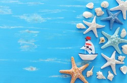vacation and summer concept with vintage boat starfish and seashells over blue wooden background. Top view flat lay