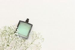 Top view of elegant perfume bottle with flowers over wooden white background. Cosmetics, fragrance and perfumery concept