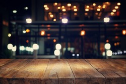 image of wooden table in front of abstract blurred background of resturant lights
