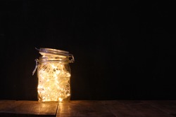 low key and vintage filtered image of fairy lights in mason jar with. selective focus
