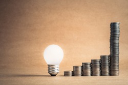 Glowing light bulb with heap coins stair that sudden steep higher progress in the last step, high earnings or success in the long term for finance and business concept