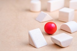 A wooden red ball in a group of other geometric wood toys as business strategy, position in the market, define the target