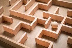 Wooden blocks maze game with wooden ball as subject to find the exit, complicated issue, busy and complex event