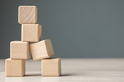 Wooden cubes are built as a tower and risk falling down caused by the only one on the base is in the wrong composition, looking unstable and fragile. Weakest one in a teamwork