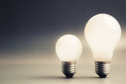 Comparative big and small light bulb, small and medium sized business, coaching, training, or other comparison concept
