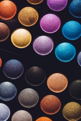 Colorful eyeshadows in rows on a black background. Professional makeup set. Flat lay.