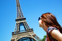 Young attractive happy woman looking at Eiffel Tower in Paris, France