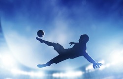 Football, soccer match. A player shooting on goal performing a bicycle kick. Lights on the stadium at night.