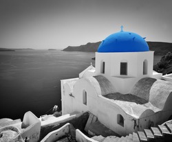 Oia town on Santorini island, Greece. Black and white styled with blue dome of traditional church over the Caldera, Aegean sea
