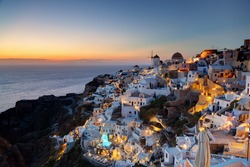 Oia town on Santorini island, Greece at sunset. Traditional and famous windmills on cliff over the Caldera, Aegean sea.