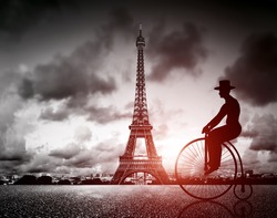 Man on retro bicycle next to Effel Tower, Paris, France. Black and white, vintage mood and red sun light