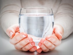 A glass of clean mineral water in woman's hands. Concept of environment protection, healthy drink.