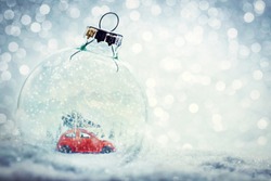 Christmas glass ball in snow with miniature winter world inside - car with Christmas tree, mountains. Glitter background.