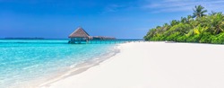 Panorama of wide sandy beach on a tropical island in Maldives. Coconut palms and water lodge on Indian Ocean.