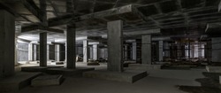 Construction of building basement, panorama inside dark construction site. Commercial structure under construction with concrete walls and floor. Concept of factory, parking, underground and industry
