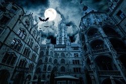 Marienplatz at night, Munich, Germany. Creepy mystery view of dark Gothic Town Hall with bats. Old spooky castle or palace in full moon. Scary gloomy scene with horror and terror for Halloween theme.