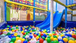 Playground for sport and play in kindergarten. Panoramic view inside the plastic dry pool with colorful balls and slide. Nice kids gym for activity in playroom. Modern children playground indoor.