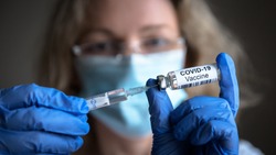 COVID-19 vaccine in researcher hands, female doctor's holds syringe and bottle with vaccine for coronavirus cure. Concept of corona virus treatment, injection, shot and clinical trial during pandemic