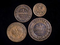 Old Russian coins 19th century, copper money on black background. Top view of vintage coins of Russia with monogram and Imperial coat of arms. Concept of rare coin, antique currency and numismatics.