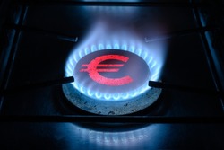 Gas ring burner and Euro sign, European money symbol on home gas stove. Blue propane flame and currency. Concept of energy crisis, Europe economy, oil, expensive cost, sanctions, payment and saving.