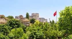 Walls of Constantinople with Turkish flag, Istanbul, Turkey. It is a famous landmark of Istanbul. Panorama of the ancient urban fortress walls in summer. Scenic view of Byzantine ruins in Istanbul.