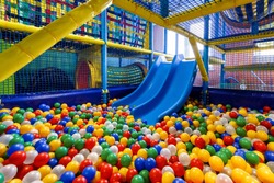 Modern children playground indoor. Inside the beautiful kids playground with a slide. Panoramic view of plastic dry pool with colorful balls for playing. 