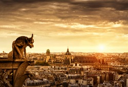 Gargoyle on Cathedral of Notre Dame de Paris overlooking city at sunset, France. Panorama of Paris with old Gothic statue in sunlight. Sunny view of Paris from Notre Dame roof. Dramatic sky background