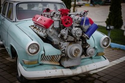 Image of a vintage tuned car, with a large engine sticking out of its hood.